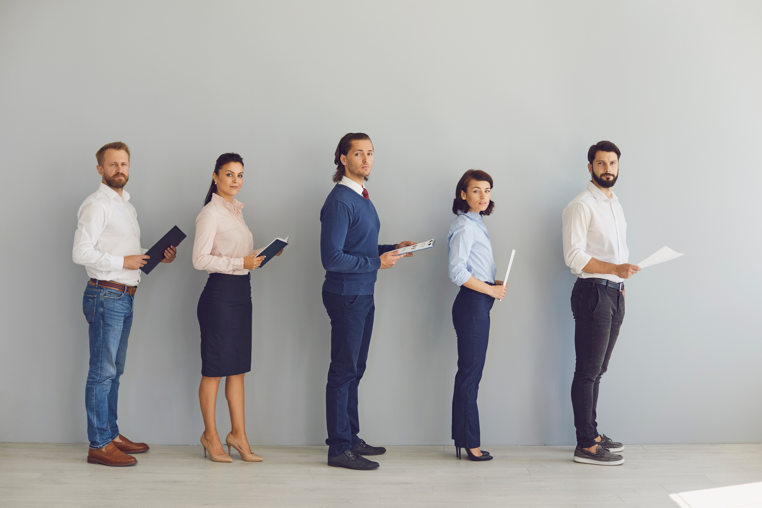 Job Applicants with CVs in Hands Lining up in Corridor Waiting to Be Interviewed